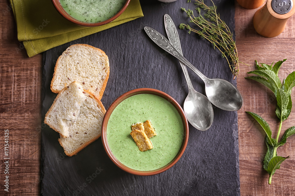 Puree from green peas in bowl with rusks on table