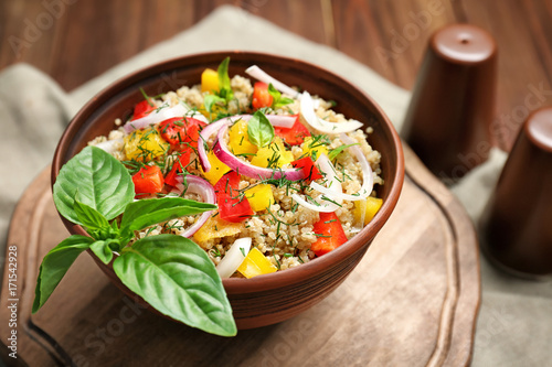 Salad with quinoa, tomatoes and basil leaves served on kitchen table