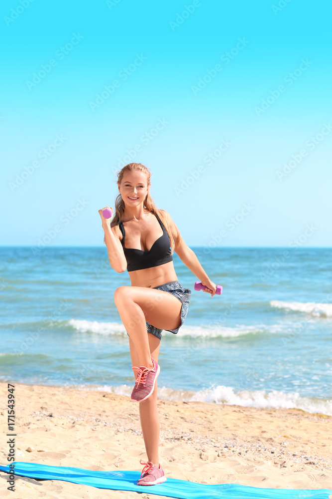 Sporty young woman training on sea beach