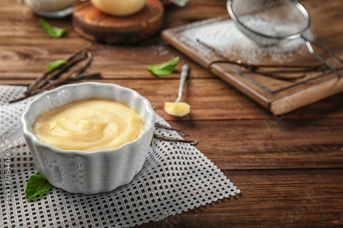 Vanilla pudding in ceramic bowl on wooden table