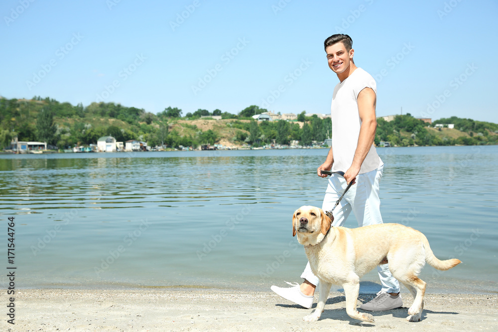 Young man walking yellow retriever near river Young man walking yellow retriever near river