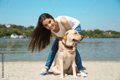 Young woman resting with yellow retriever near river