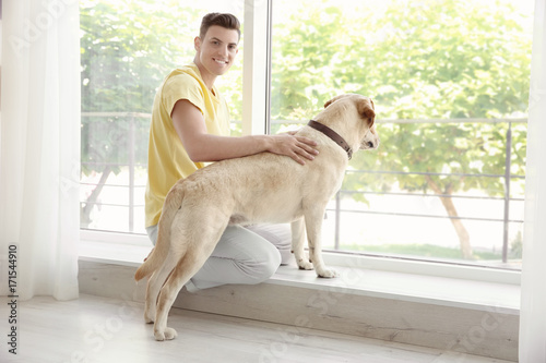 Young man sitting with yellow retriever near window