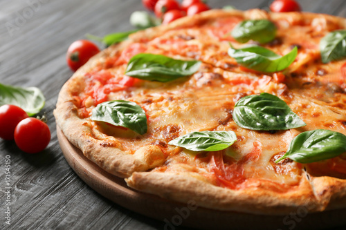 Delicious pizza with tomatoes and fresh basil on kitchen table