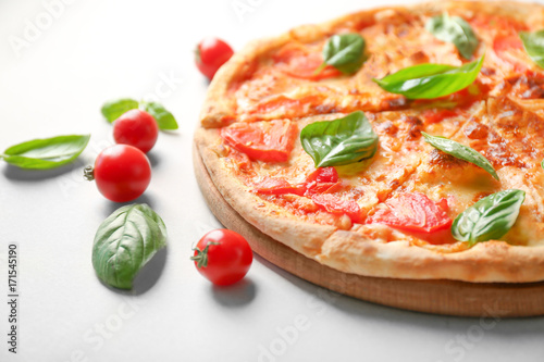 Delicious pizza, cherry tomatoes and fresh basil on light background