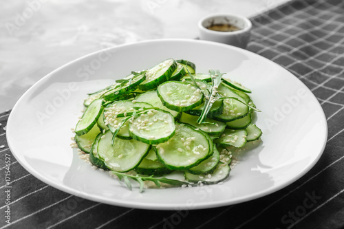 Plate with fresh cucumber salad on table