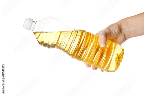Female hand holding plastic bottle with cooking oil, on white background
