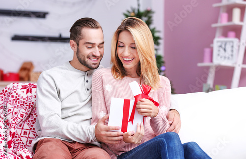 Happy young couple with Christmas present at home