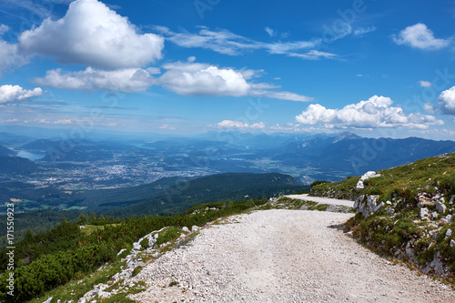 Gravel foot path in Dobratsch Nature Park with panorama view over a valley with the city of Villach in Austria