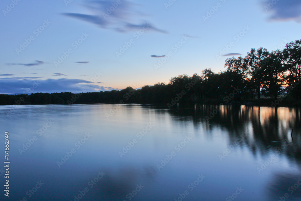 Obraz premium Sunset on pond with trees silhouette and orange sky, long exposure, Czech landscape