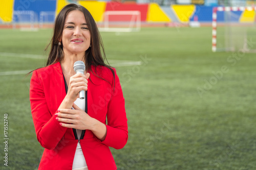 Young attractive journalist is reporting from the stadium photo