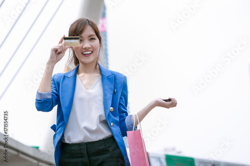 asian woman shopping smile and holding credit card and shopping bag with shopping mall background  consumerism  sale and people online concept