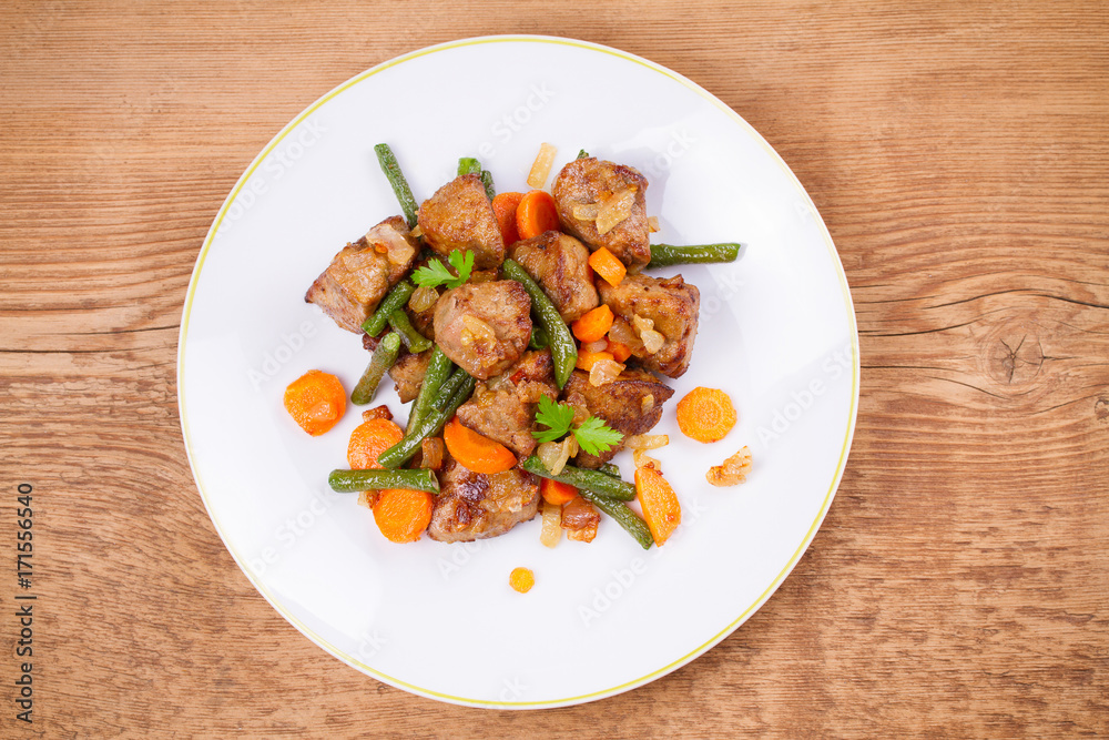 Beef liver with vegetables: carrot, onion and green beans on white plate. Top, overhead, above view, horizontal