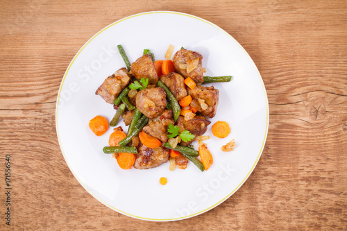 Beef liver with vegetables: carrot, onion and green beans on white plate. Top, overhead, above view, horizontal