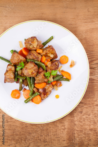 Beef liver with vegetables: carrot, onion and green beans on white plate. Top, overhead, above view, vertical