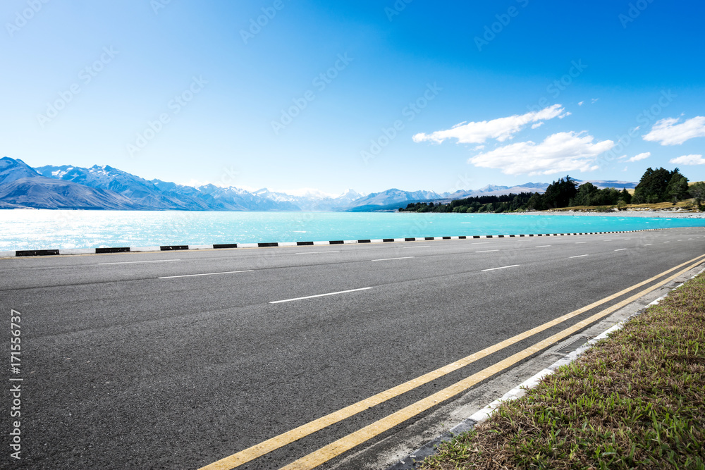 empty asphalt road with beautiful lake in blue sky