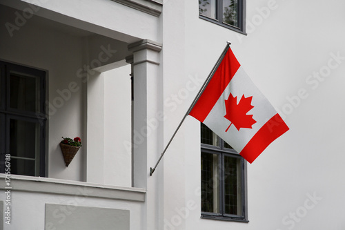 Canada flag. Canadian flag displaying on a pole in front of the house. National flag of Canada waving on a home hanging from a pole on a front door of a building. photo