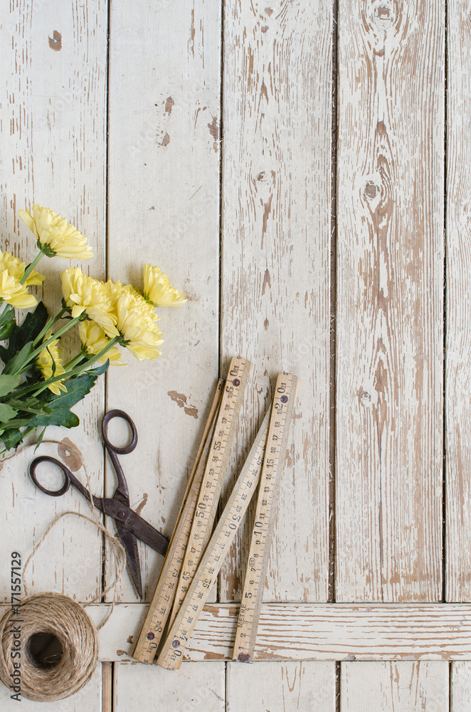 Flores amarillas con tijeras y ovillo de cuerda y metro de carpintero sobre  fondo de tablones de madera envejecida Stock Photo | Adobe Stock