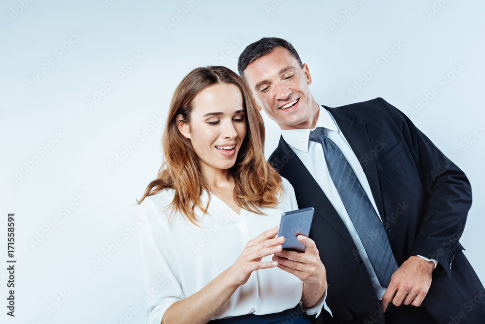 Friendly colleagues sharing photos on smartphone Friendly colleagues sharing photos on smartphone