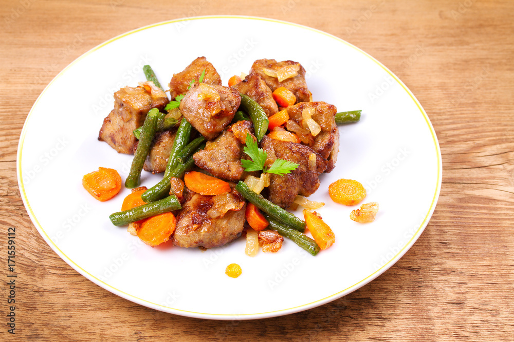 Beef liver with vegetables: carrot, onion and green beans on white plate, horizontal Beef liver with vegetables: carrot, onion and green beans on white plate, horizontal