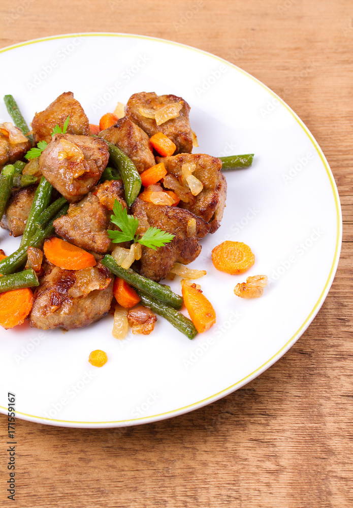 Beef liver with vegetables: carrot, onion and green beans on white plate, vertical Beef liver with vegetables: carrot, onion and green beans on white plate, vertical