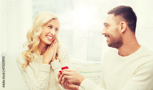 happy man giving engagement ring to woman at home