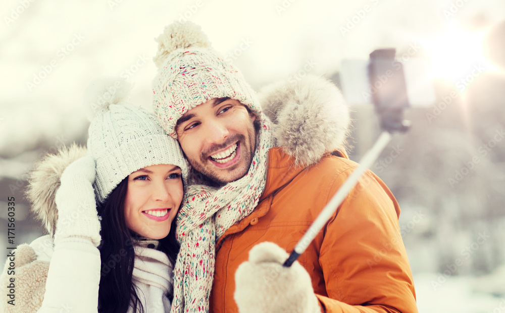 happy couple taking selfie by smartphone in winter
