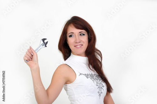 studio portrait of a smiling confident capable working woman holding a spanner photo