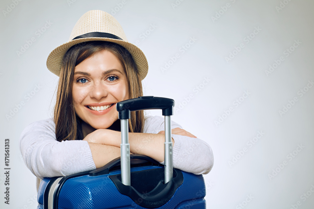 Smiling woman with folded hands on suitcase