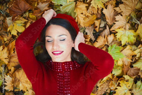 Caucasian girl laying down on leafs at the autumn