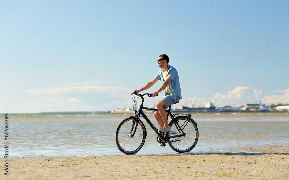 happy man riding bicycle along summer beach