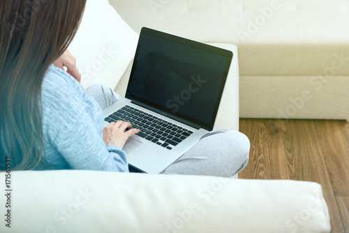 woman sitting back on sofa with laptop.