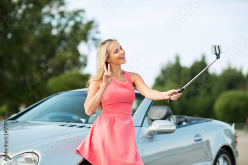 woman taking picture by selfie stick at car © Syda Productions