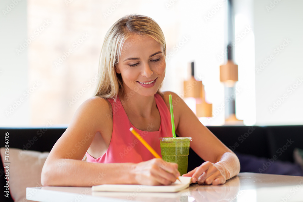 woman with drink writing to notebook at restaurant