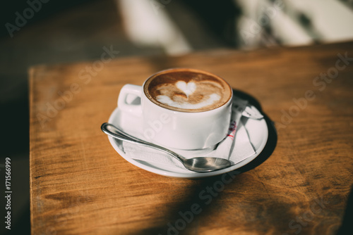Чашка кофе стоит на деревянном столе 