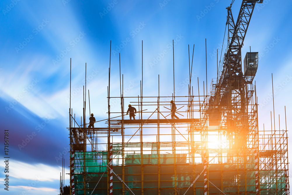 Fotografie Construction site with crane and workers at sunset