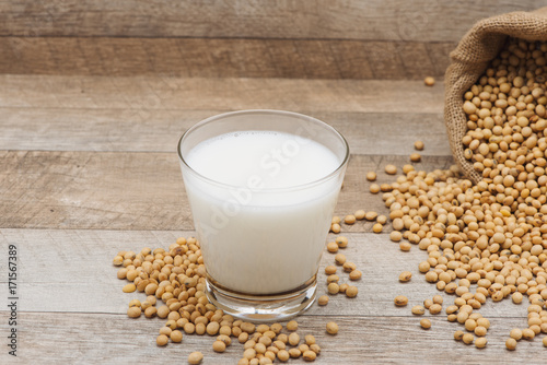 Glass with soy milk and soy bean on wooden background