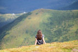 The girl is sitting on the edge of the mountain