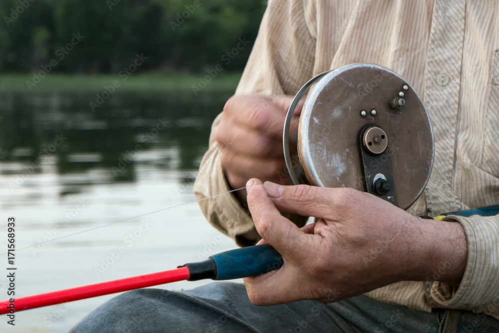 Coil spinning. Horizontally. The fisherman's arms wind the forest with a vintage  spinning reel Stock Photo