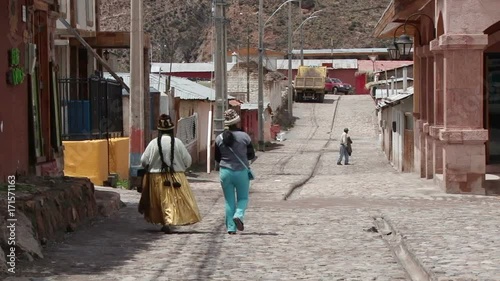 Local women are walking down old pebble street in Putre, Chile photo