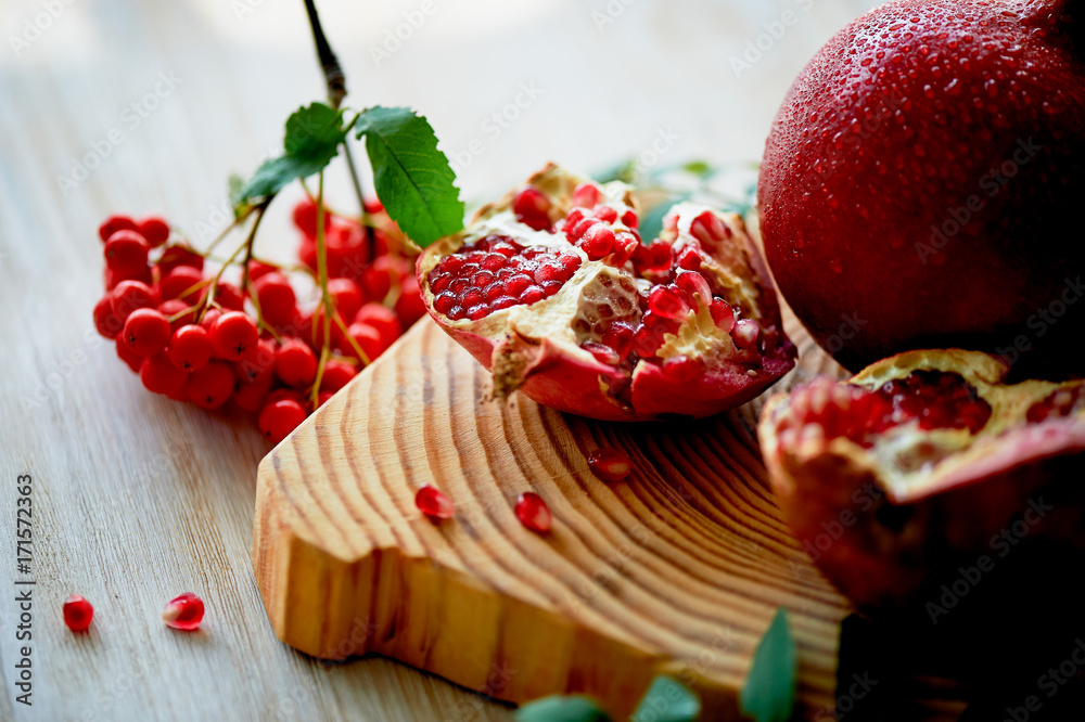 Fresh juicy pomegranate on a light background. On the wooden end of it. Next brush the ash. Healthy eating. Vegetarianism Fresh juicy pomegranate on a light background. On the wooden end of it. Next brush the ash. Healthy eating. Vegetarianism