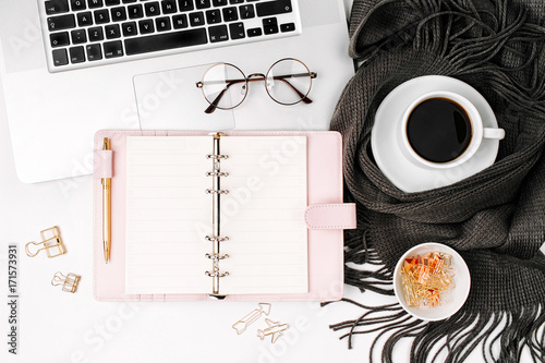 Workspace with laptop, open planner mockup, coffee cup wrapped in scarf,  glasses. Stylish office desk. Autumn or Winter concept.  Flat lay, top view