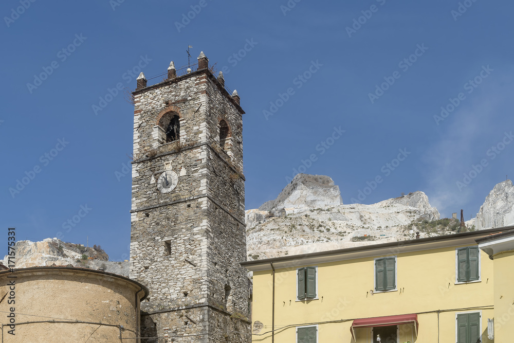 View of the bell tower of the church of San Bartolomeo in the ancient village of Colonnata, Massa Carrara, Tuscany, Italy, against marble quarries in the Apuan Alps