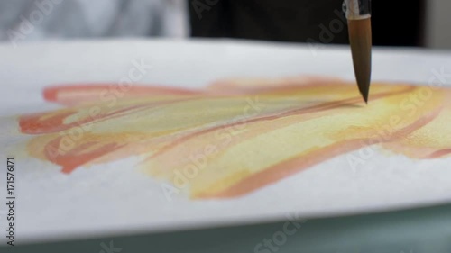 Artist painting watercolor paints on wet paper