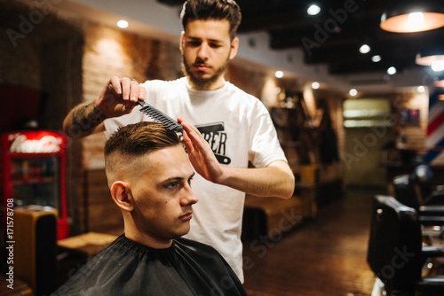 Billede på lærred Barber is combing the client's hair comb