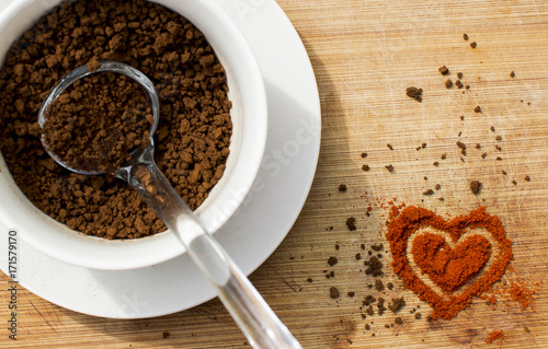 Kawa rozpuszczalna w filiżance i serduszko ułożone z przypraw.