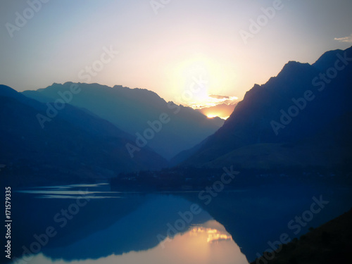 Lake in the mountains. Mirror surface of water at sunrise. Bench and hearth