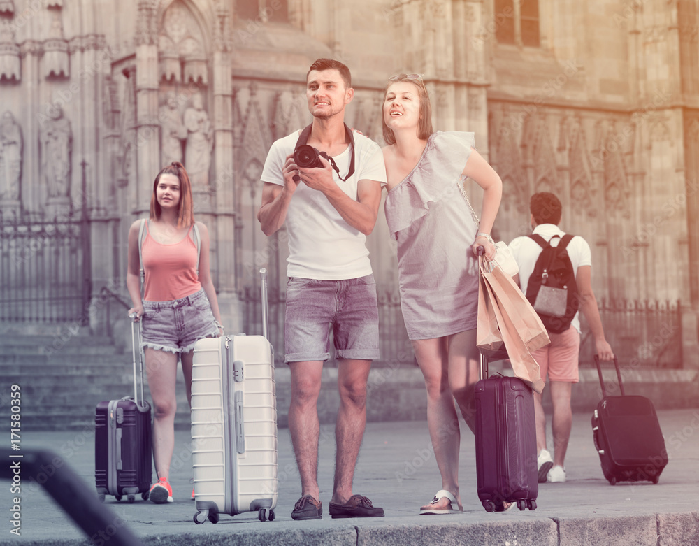 Fototapeta premium Smiling man and woman tourists are holding camera in hands and p