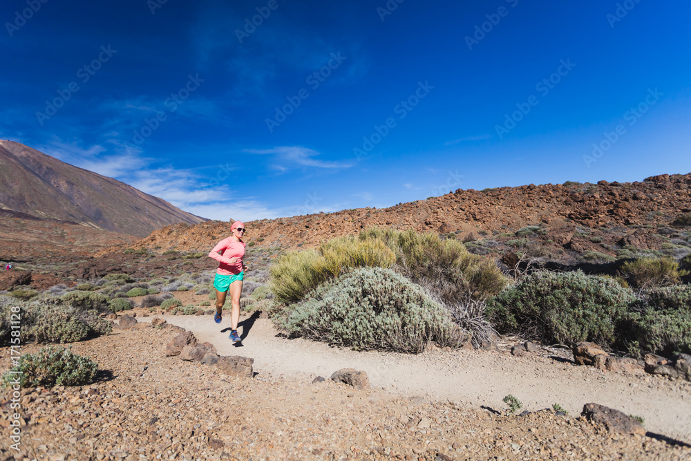 Woman running in mountains on sunny summer day