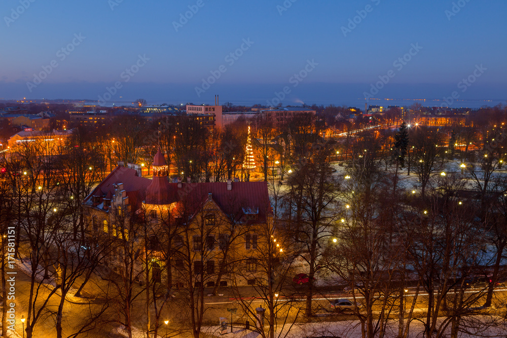 Exiting winter view of night old town of Tallinn. Aerial over park with sea.